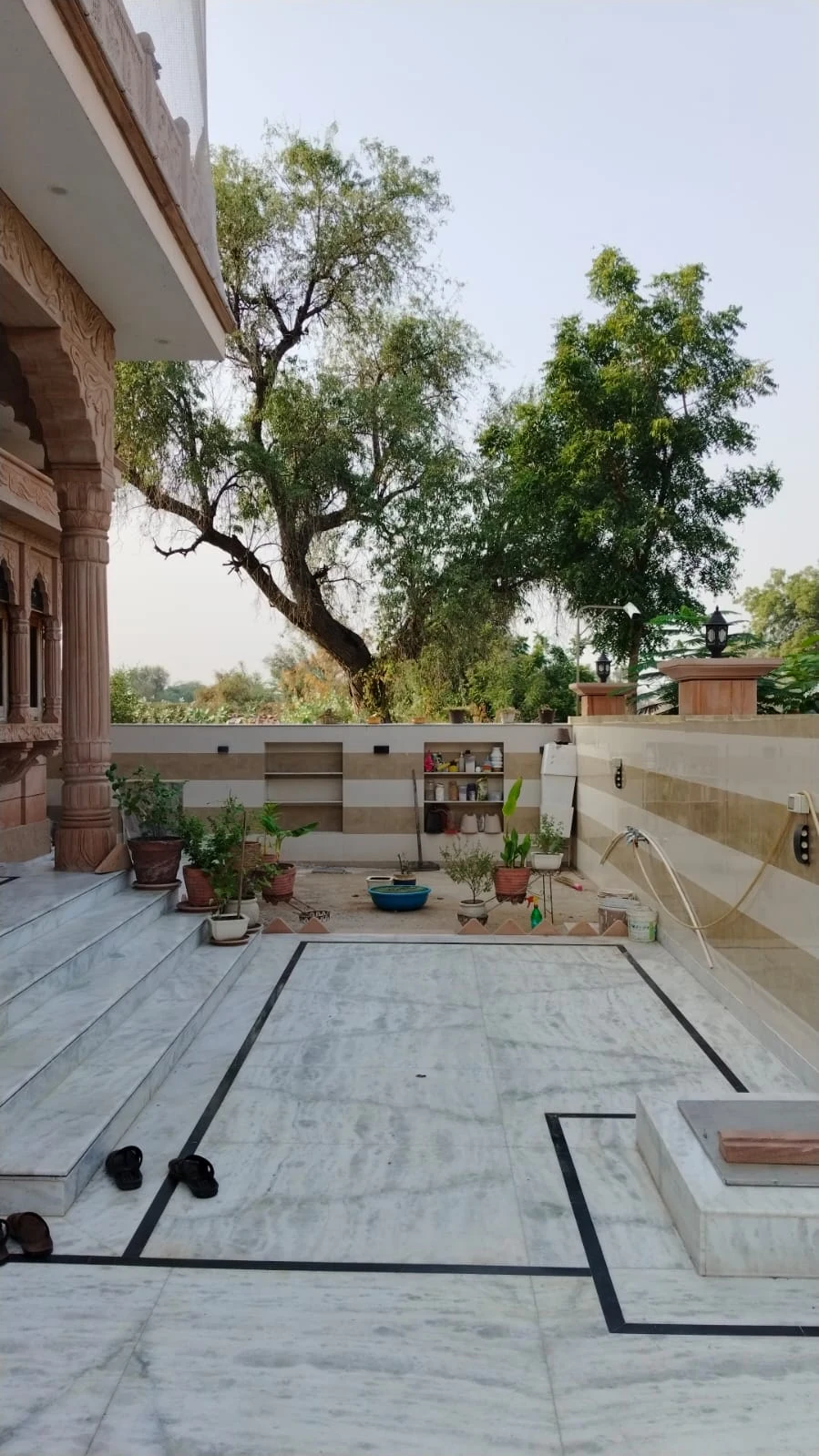 Ground-floor outdoor passage beside the haveli, looking toward the boundary wall and tree